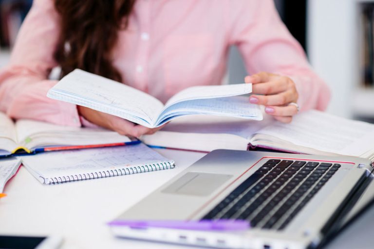 mujer estudiando en su libreta y ordenador