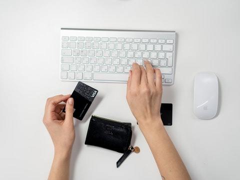 persona tecleando con una tarjeta de crédito
